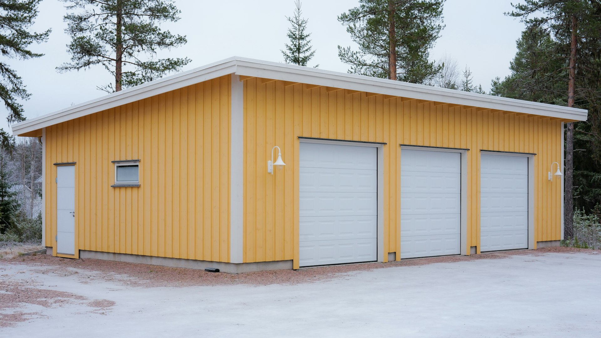 A bright yellow garage with three doors in snow